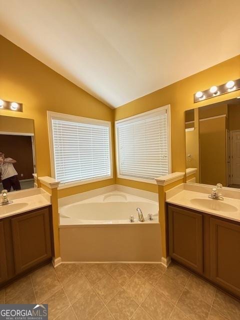 bathroom featuring a sink, a garden tub, two vanities, and vaulted ceiling