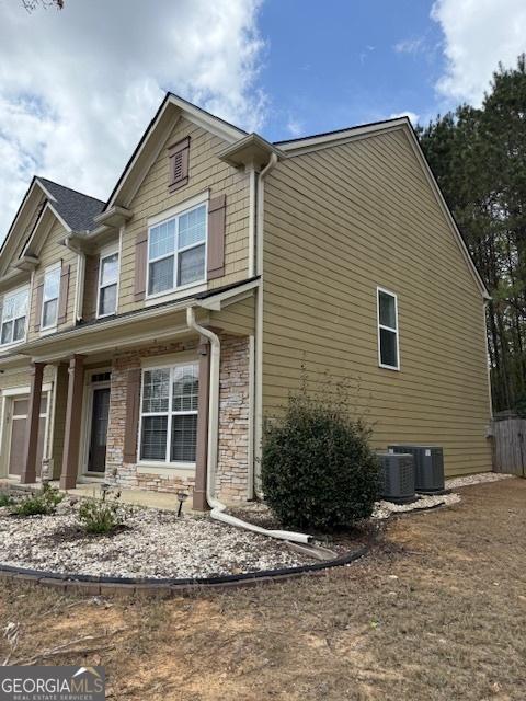 view of side of home featuring stone siding and cooling unit
