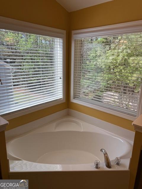 bathroom with vaulted ceiling and a garden tub