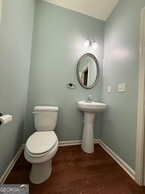 bathroom with baseboards, toilet, and wood finished floors