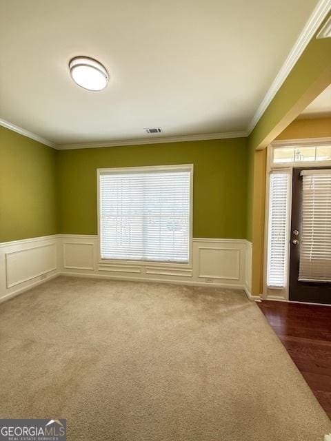 interior space with wainscoting, ornamental molding, carpet, and visible vents