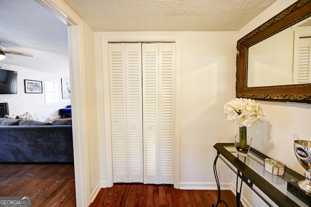 corridor featuring baseboards, dark wood-style flooring, and a textured ceiling