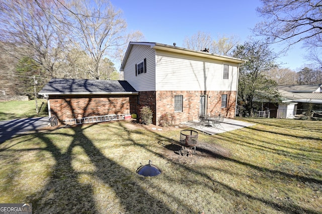 back of property with an outdoor fire pit, a patio area, brick siding, and a yard