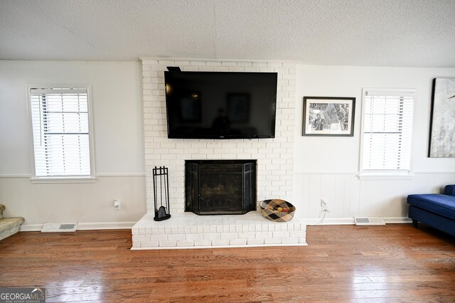 living area with visible vents, a textured ceiling, and wood finished floors