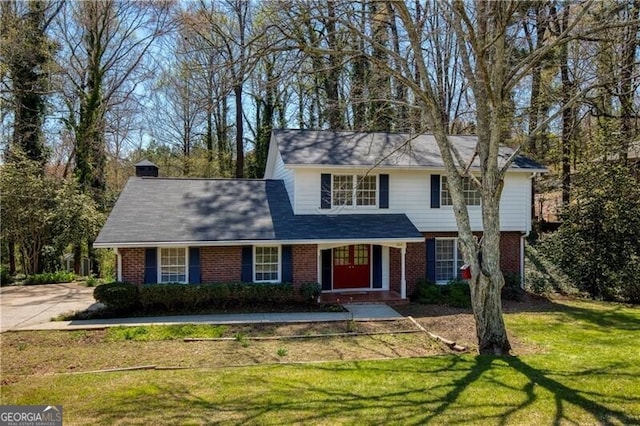 traditional home featuring a front yard and brick siding