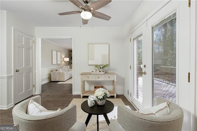living area with baseboards, ornamental molding, a ceiling fan, and dark wood finished floors