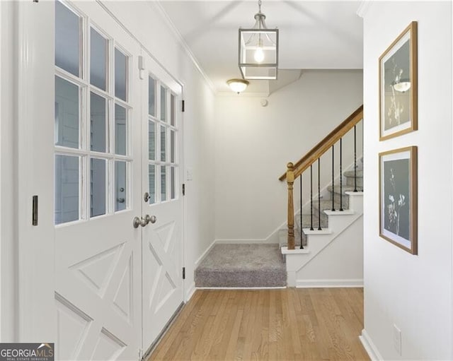 entrance foyer featuring baseboards, ornamental molding, wood finished floors, and stairway