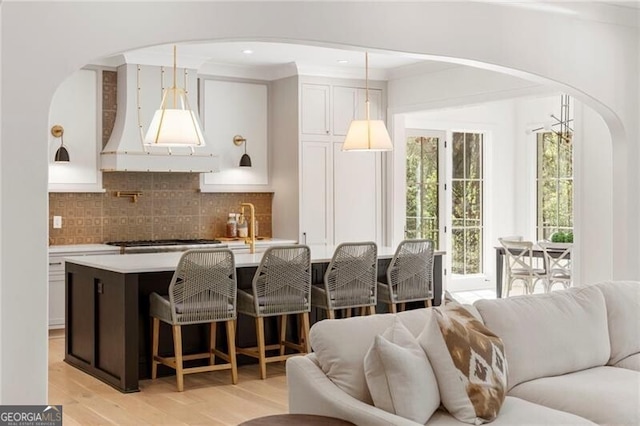 1074 Moores Mill Rd NW, Atlanta, GA 30327 - kitchen featuring arched walkways, open floor plan, light wood finished floors, stainless steel gas cooktop, and light countertops