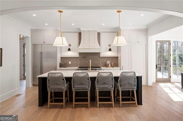 1074 Moores Mill Rd NW, Atlanta, GA 30327 - kitchen with custom exhaust hood, built in refrigerator, ornamental molding, arched walkways, and light countertops