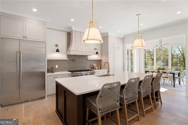 1074 Moores Mill Rd NW, Atlanta, GA 30327 - kitchen with stainless steel built in fridge, wall chimney range hood, tasteful backsplash, light countertops, and light wood-type flooring