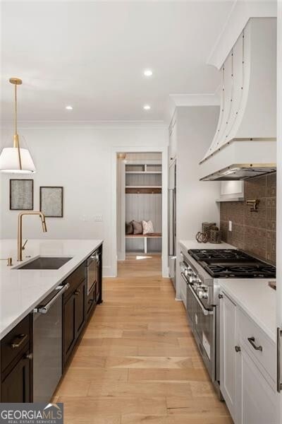 1074 Moores Mill Rd NW, Atlanta, GA 30327 - kitchen with stainless steel appliances, light countertops, ornamental molding, hanging light fixtures, and light wood-style floors