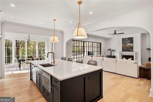 1074 Moores Mill Rd NW, Atlanta, GA 30327 - kitchen featuring a ceiling fan, arched walkways, stainless steel microwave, light wood finished floors, and light countertops
