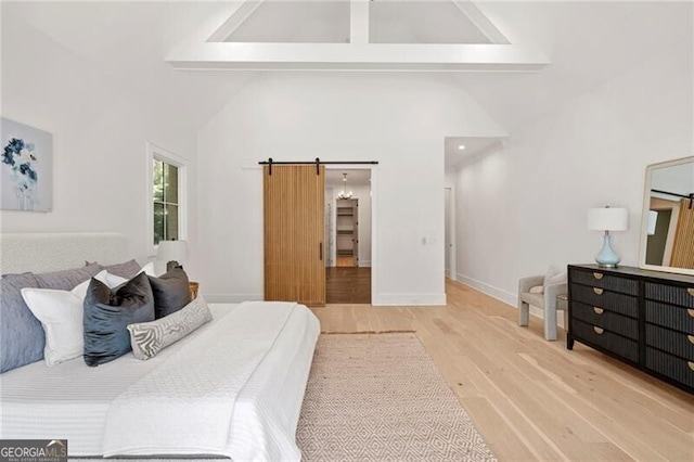 1074 Moores Mill Rd NW, Atlanta, GA 30327 - bedroom featuring a barn door, wood finished floors, high vaulted ceiling, and beam ceiling