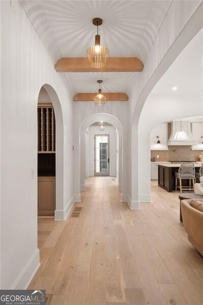 1074 Moores Mill Rd NW, Atlanta, GA 30327 - hall with arched walkways, light wood-style flooring, and beamed ceiling