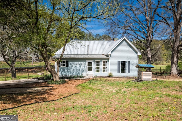 back of house featuring a lawn and metal roof