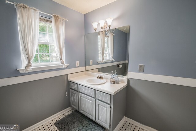 bathroom featuring baseboards, a chandelier, and vanity