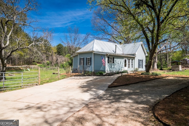 view of front of home featuring driveway, metal roof, fence, and a front yard