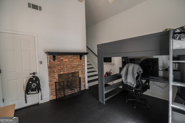 bedroom featuring a brick fireplace, wood finished floors, and visible vents