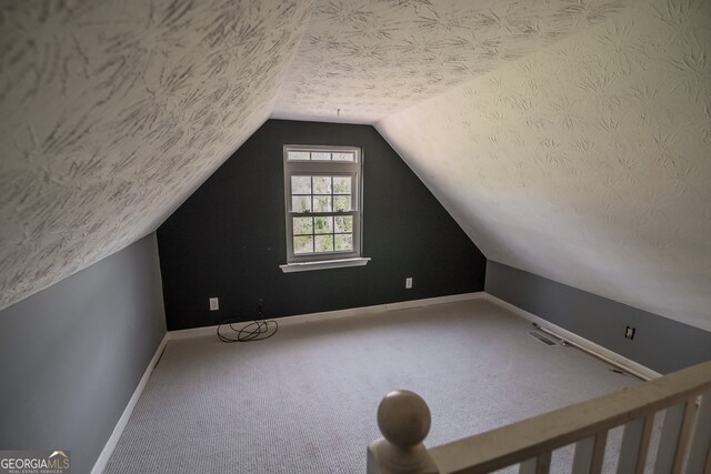 additional living space with baseboards, carpet flooring, a textured ceiling, and lofted ceiling