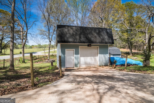 view of outdoor structure featuring fence, an outdoor structure, and concrete driveway