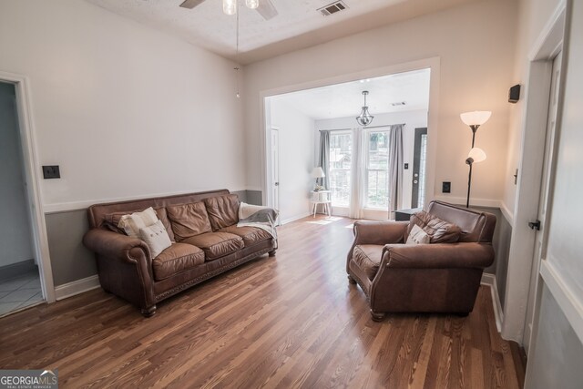 living area featuring baseboards, visible vents, wood finished floors, and a ceiling fan