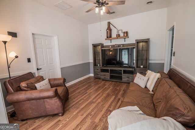 living area featuring baseboards, visible vents, wood finished floors, and a ceiling fan