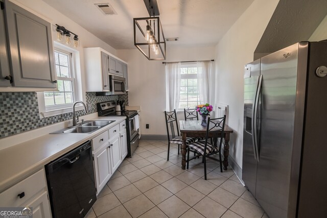 kitchen with stainless steel appliances, decorative backsplash, a sink, a wealth of natural light, and visible vents
