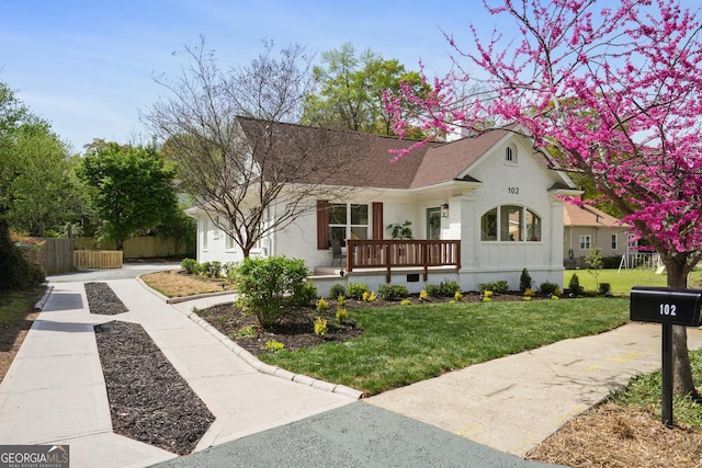 view of front of home featuring a front lawn, a shingled roof, fence, and brick siding