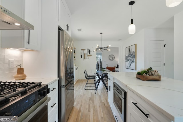 kitchen featuring white cabinetry, under cabinet range hood, stainless steel appliances, visible vents, and light wood-style floors