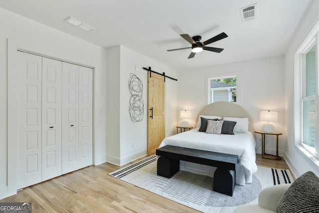 bedroom with a barn door, visible vents, and wood finished floors