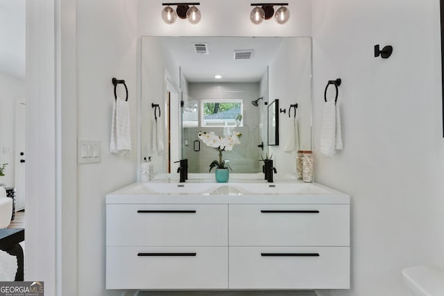 bathroom with double vanity, a sink, a shower stall, and visible vents