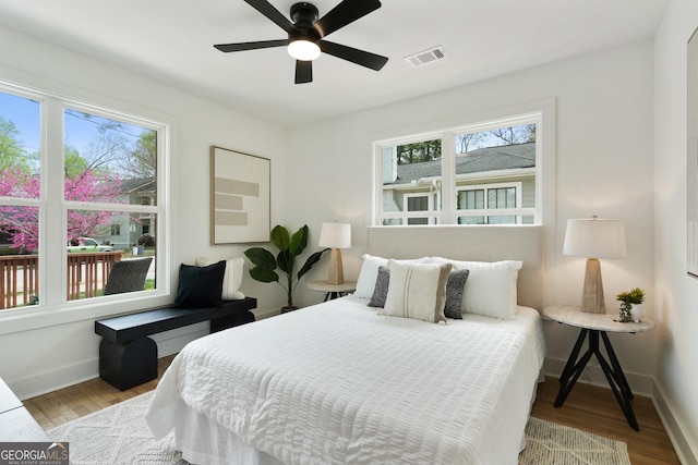bedroom with multiple windows, visible vents, and wood finished floors