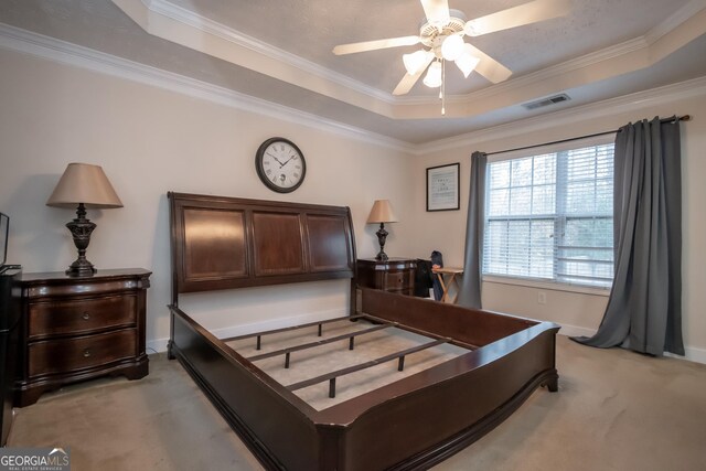 bedroom featuring light colored carpet, ornamental molding, baseboards, a raised ceiling, and visible vents
