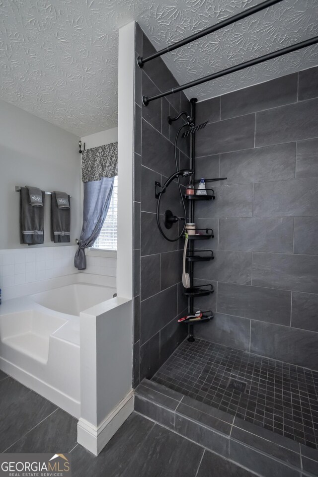 full bathroom featuring tile patterned floors, a garden tub, a tile shower, and a textured ceiling