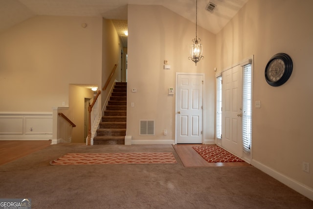 entryway with stairs, visible vents, high vaulted ceiling, and carpet floors