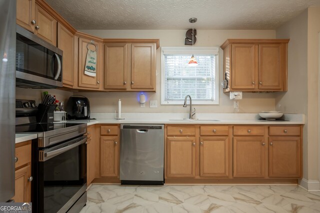 kitchen with marble finish floor, light countertops, a sink, and appliances with stainless steel finishes
