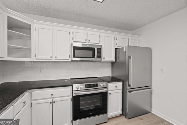 kitchen featuring white cabinetry, backsplash, light wood-style flooring, and appliances with stainless steel finishes