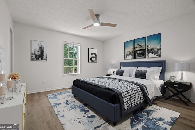 bedroom featuring a textured ceiling, baseboards, ceiling fan, and wood finished floors
