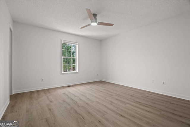 unfurnished room with a textured ceiling, baseboards, ceiling fan, and wood finished floors