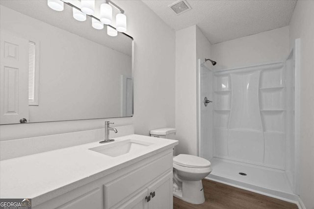 full bath featuring a stall shower, toilet, vanity, wood finished floors, and visible vents