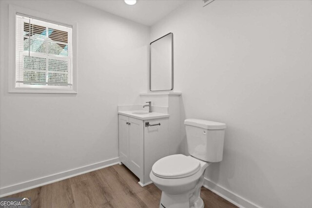 bathroom featuring toilet, vanity, baseboards, and wood finished floors