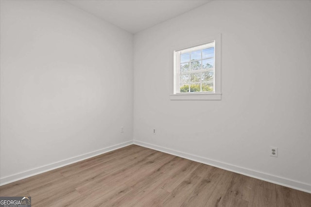 spare room with baseboards and light wood-type flooring