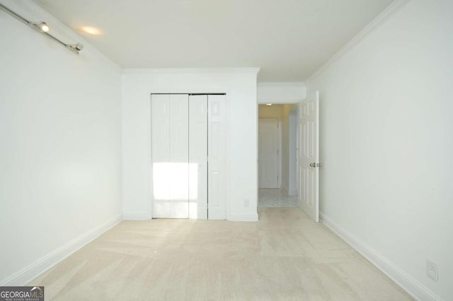unfurnished bedroom featuring baseboards, a closet, crown molding, and carpet floors
