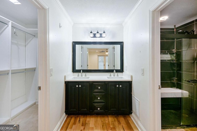 bathroom with a stall shower, double vanity, ornamental molding, and a sink