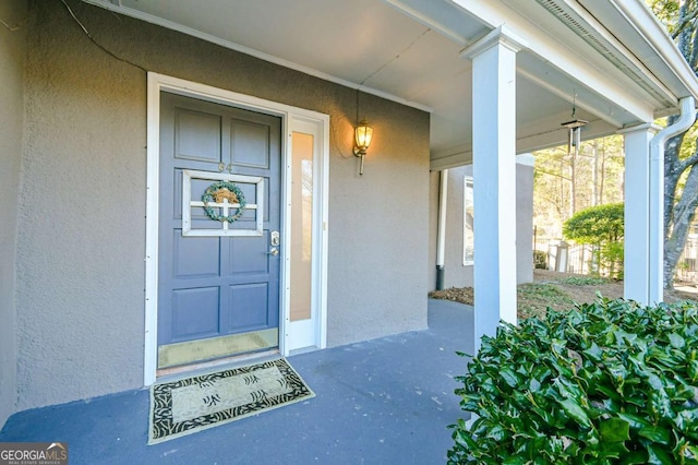 view of exterior entry featuring covered porch and stucco siding