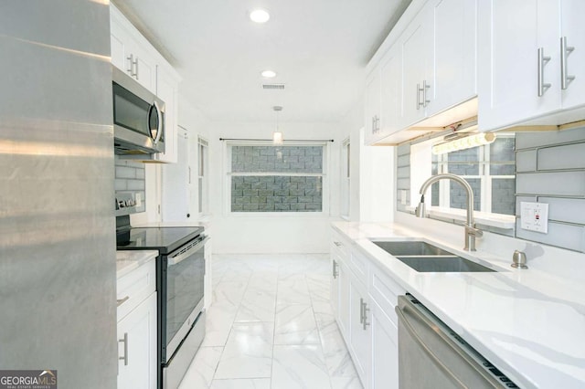 kitchen with visible vents, marble finish floor, stainless steel appliances, white cabinetry, and a sink