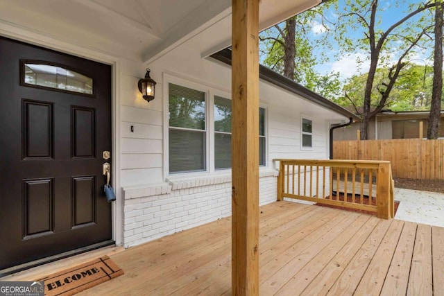view of exterior entry featuring fence and brick siding