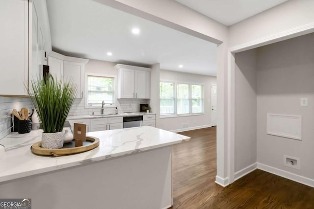 kitchen featuring dishwasher, a sink, dark wood-style floors, white cabinetry, and decorative backsplash