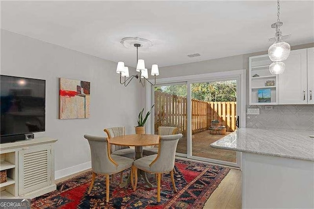 dining room with baseboards, visible vents, wood finished floors, and a notable chandelier
