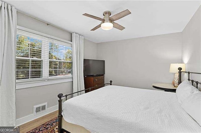 bedroom with baseboards, visible vents, a ceiling fan, and wood finished floors